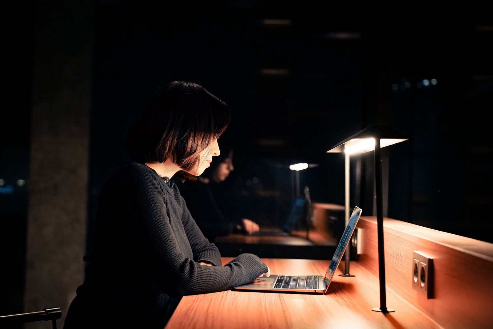 Woman focused on a laptop at a quiet desk late at night