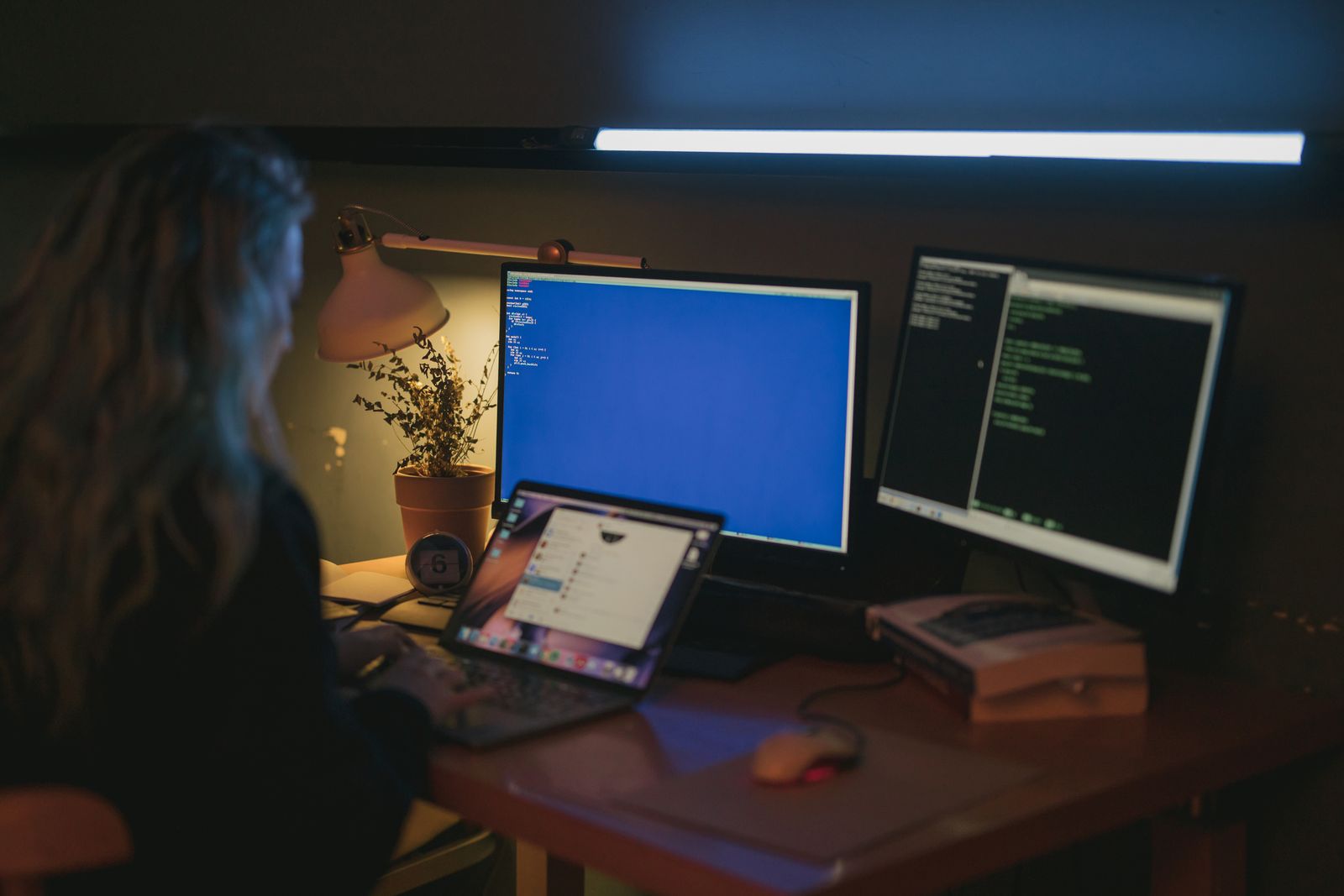 Woman using a multi-screen technology workspace in a home office